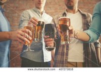 stock-photo-male-group-clinking-glasses-of-dark-and-light-beer-on-brick-wall-background-407273818